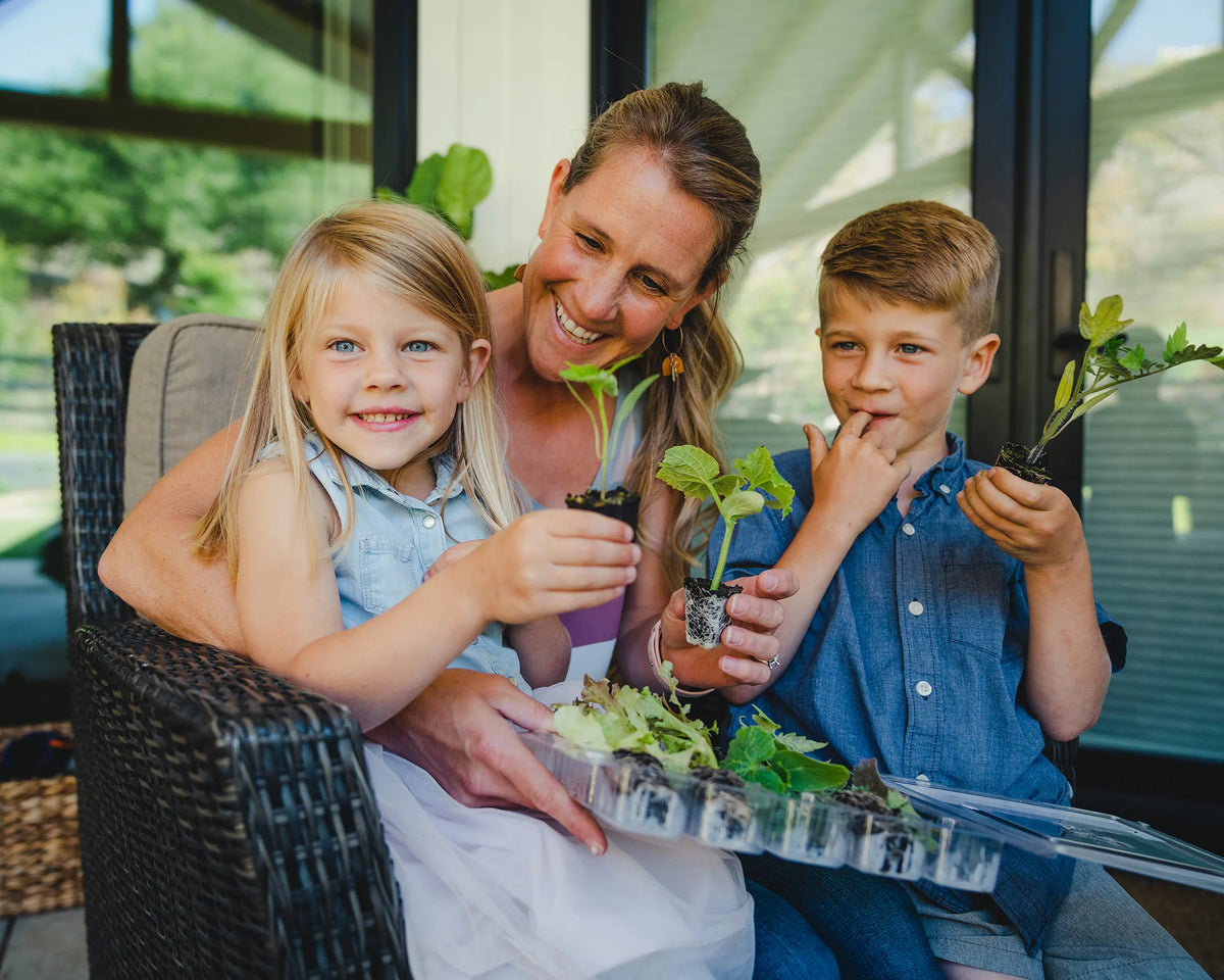 Adult and young child examining vegetables together in a garden.